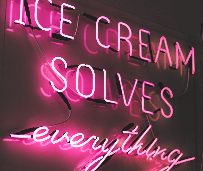Pink neon sign saying Ice Cream Solves Everything on black background